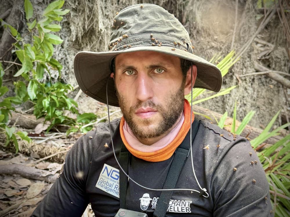 close-up portrait of a man covered in ants in an outdoor jungle environment