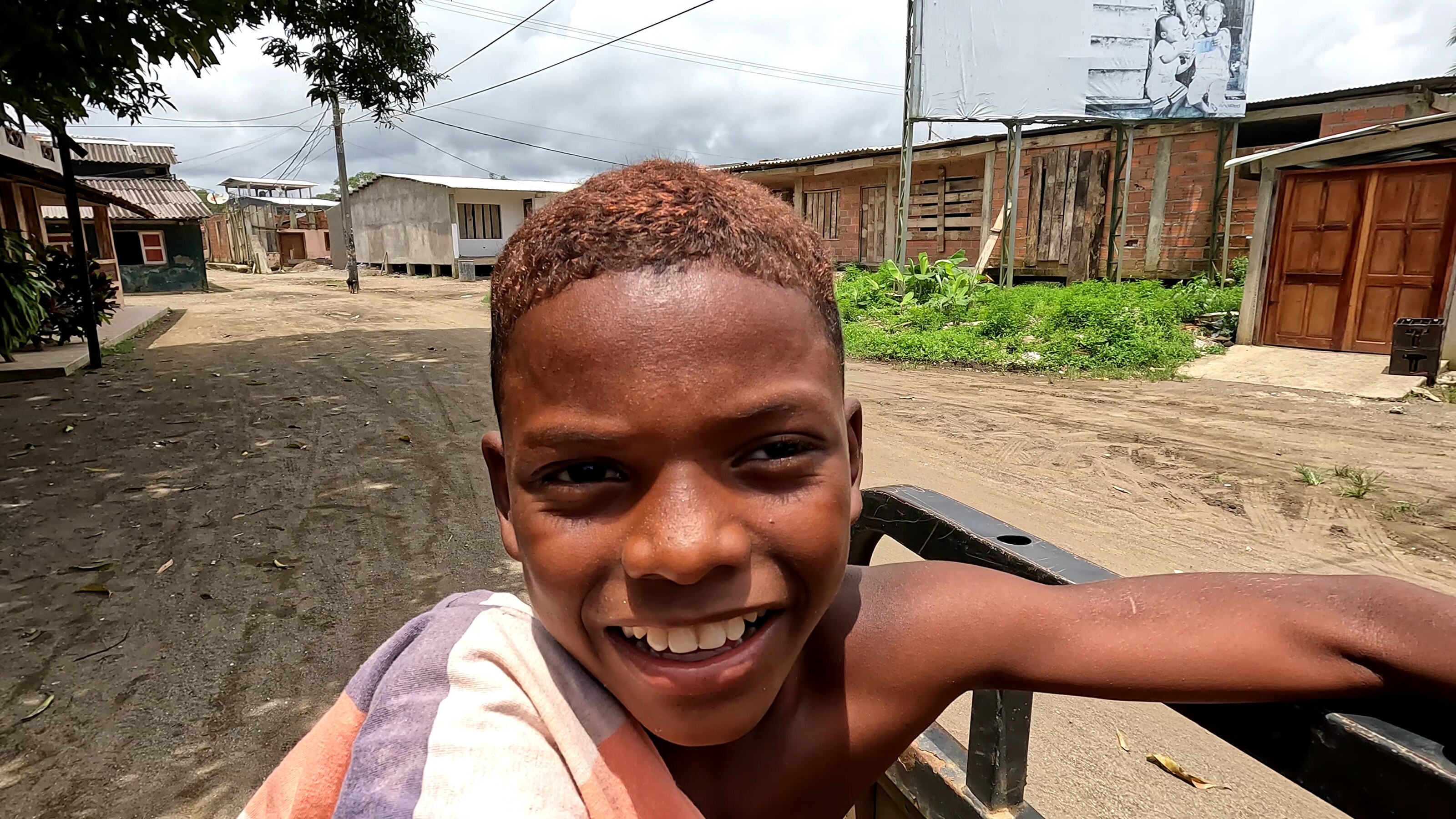 close-up portrait of a smiling boy outdoors on a rural unpaved street