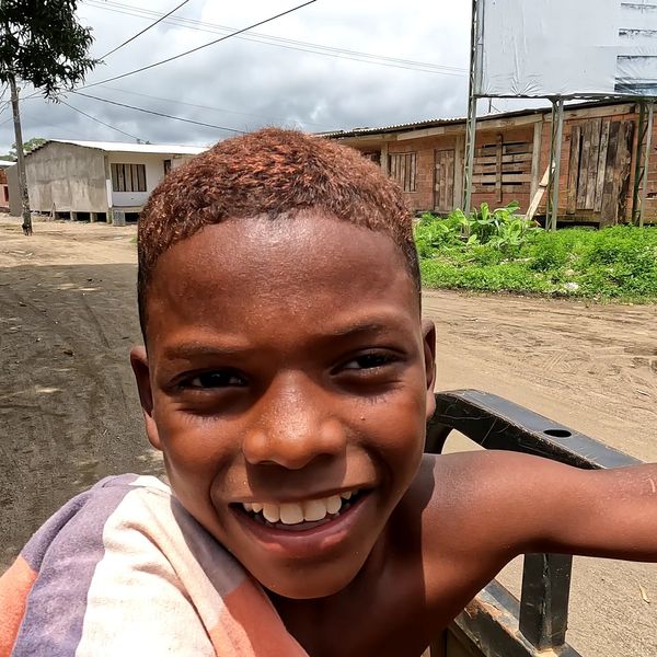 close-up portrait of a smiling boy outdoors on a rural unpaved street