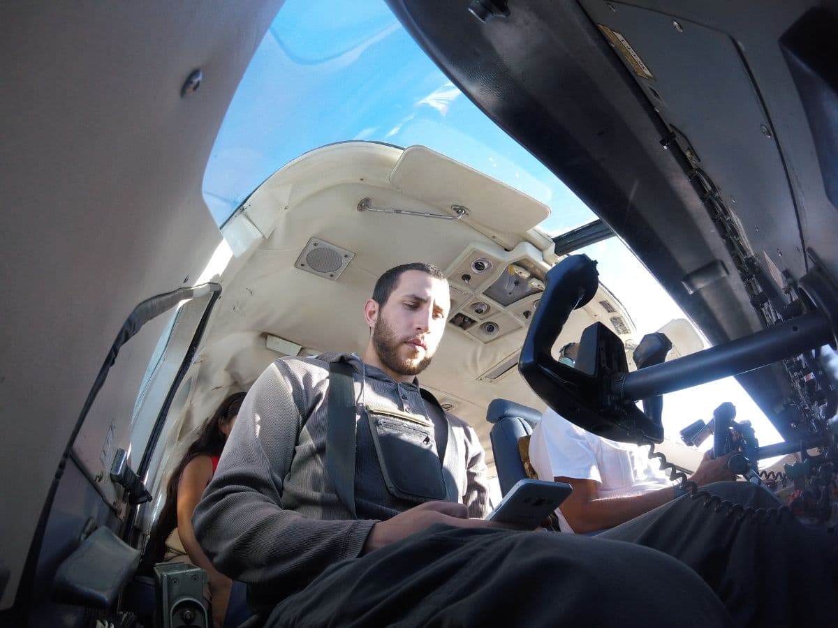 passenger inside a helicopter cabin looking at a phone, shot from a wide-angle low angle