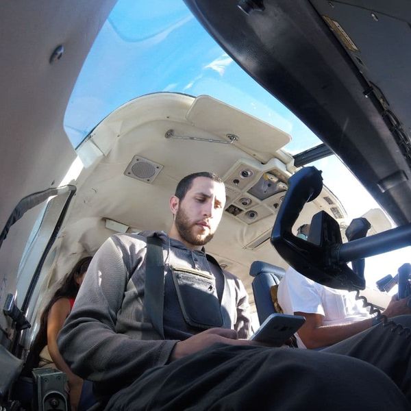 passenger inside a helicopter cabin looking at a phone, shot from a wide-angle low angle