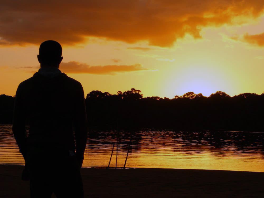 A lone figure silhouetted against a sunset on the Essequibo river