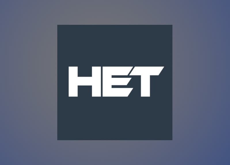 logo mark - bold white "HET" lettering with a diagonal slash detail on a dark navy square tile, on a blue-grey gradient background