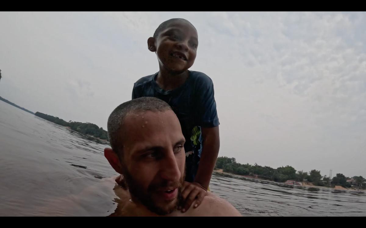 a man and a young child playing in a river, shot from water level with a wide-angle camera