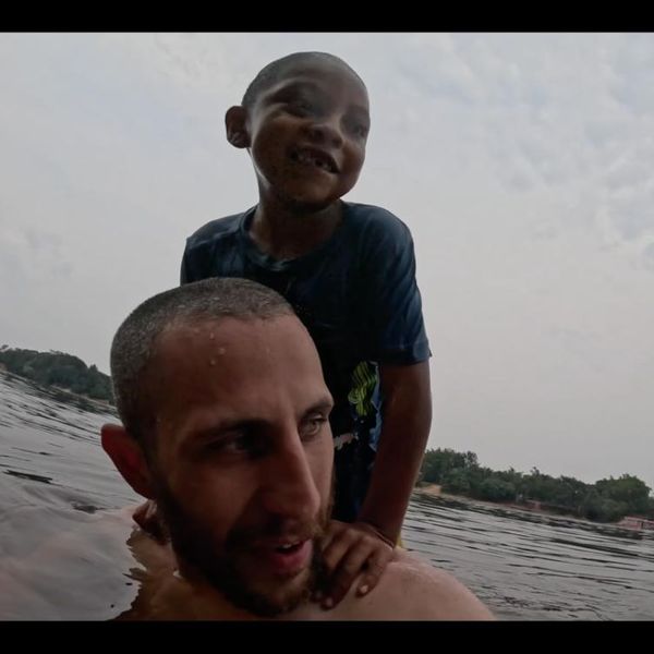 a man and a young child playing in a river, shot from water level with a wide-angle camera