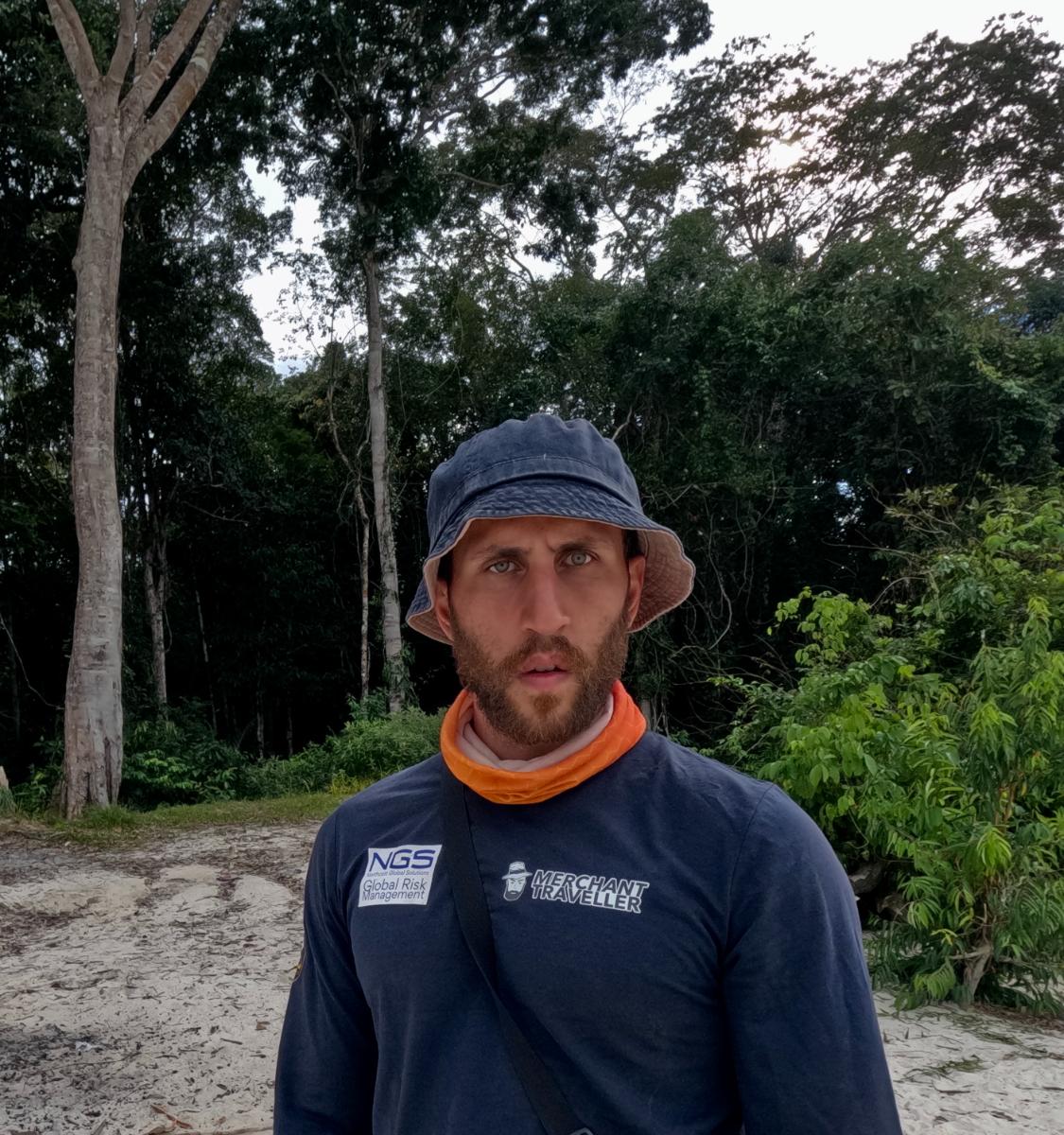 a man in branded outdoor gear posing on a sandy jungle path