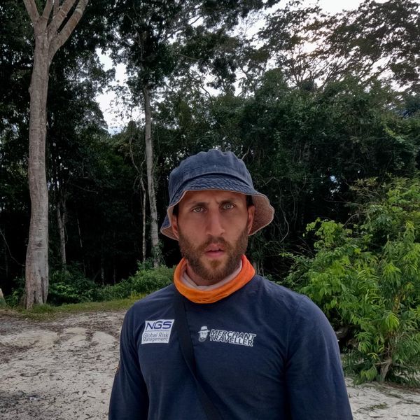 a man in branded outdoor gear posing on a sandy jungle path
