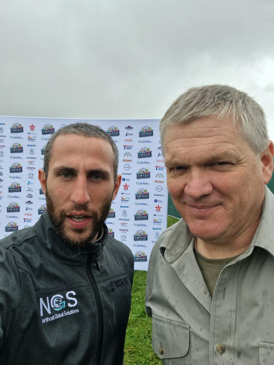 two men posing at a CarFest event sponsor backdrop, one wearing an NGS Northcott Global Solutions branded jacket