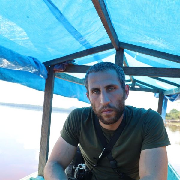 a man with a camera seated under a tarpaulin canopy on a river boat